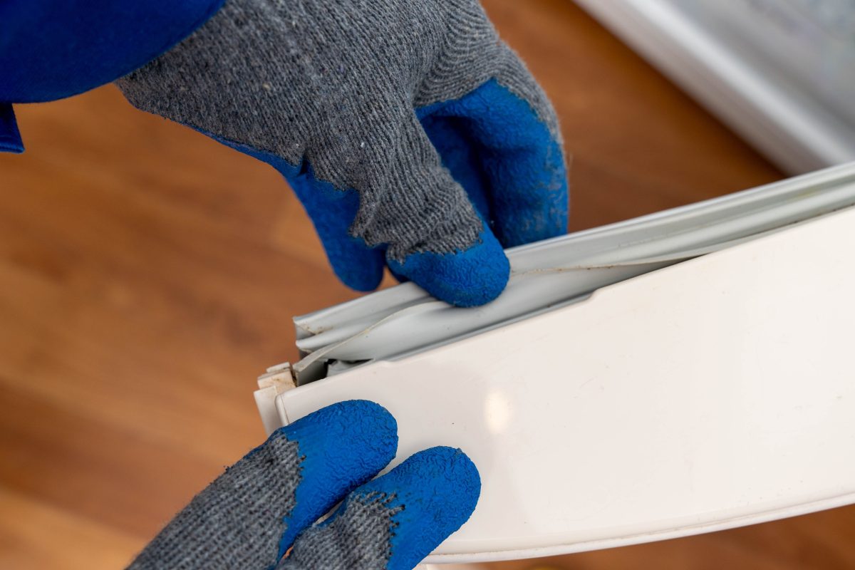 person wearing gloves reviewing the need for a fridge seal repair