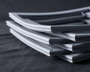 Would you pay someone £15 to carry your shopping to the car? 1 A close-up of several stacked grey rubber weatherstrips with hollow cores and angled ends, arranged diagonally on a dark, soft-textured surface. The background is black, emphasising the smooth and flexible material of the strips.