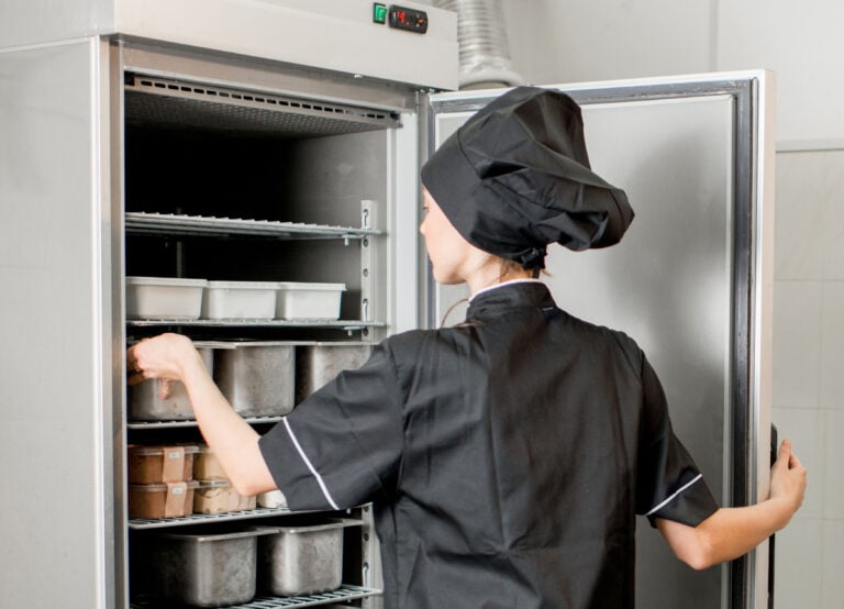 Chef cook with young woman assistant making ice cream together mixing ingredients in the professional kitchen of the small manufacturing